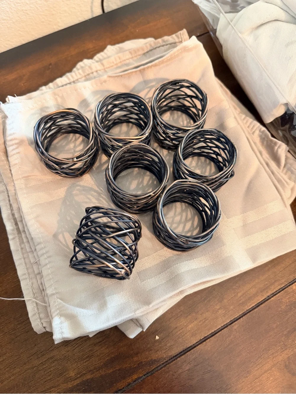 Set of 7 Black bronze Twisted Napkin Rings & beige napkins
